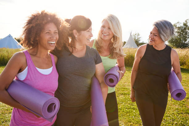 women exercise Group Of Mature Female Friends On Outdoor Yoga Retreat Walking Along Path Through Campsite